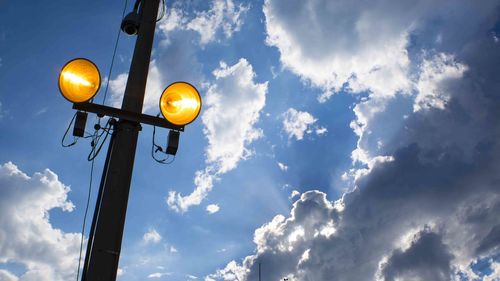 Low angle view of illuminated street light against sky