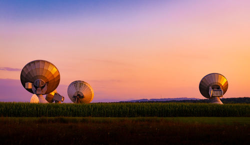 Multi colored balloons flying over field against sky during sunset