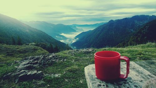 Close-up of red plastic cup on table against mountains