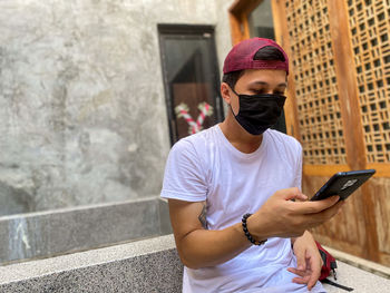 Asian man holding smartphone face mask