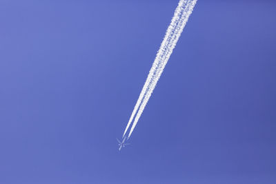 Low angle view of airplane flying against blue sky