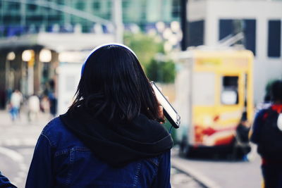 Rear view of woman with umbrella in city