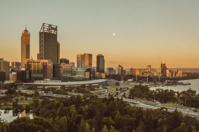 Modern buildings in city against sky during sunset