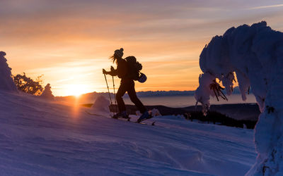 People on snow against sky during sunset