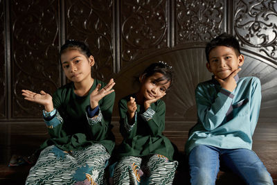 Malay kids with traditional clothing sitting together with hand gesture love