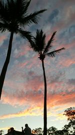 Low angle view of coconut palm trees against sky during sunset