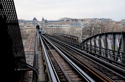 Railroad tracks in city against sky