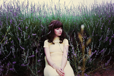 Woman standing by purple flowering plants