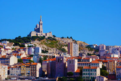 Buildings in city against clear blue sky