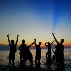 Silhouette of people on beach at sunset