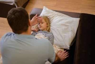 High angle view of woman using mobile phone while lying on bed at home