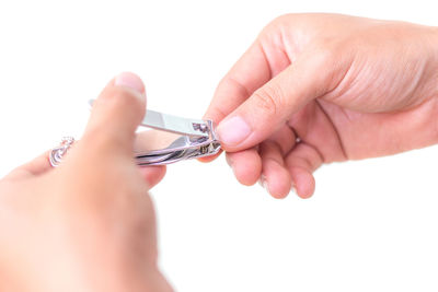 Close-up of hand holding nail clipper over white background