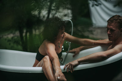Midsection of shirtless man and woman in water