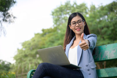 Young woman using phone while sitting on camera