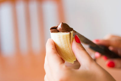 Hand holding peas of banana with chocolate on top