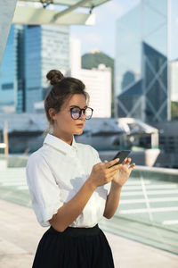 Young woman using mobile phone in city