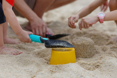 Cropped image of siblings making sand castle at beach