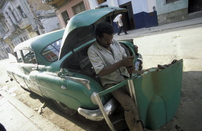 Tilt image of man repairing car on street
