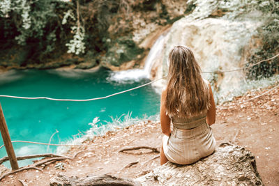 Rear view of woman sitting on rock