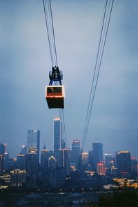 Overhead cable car and buildings against sky
