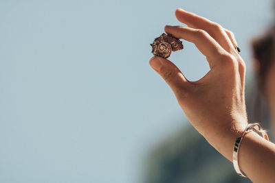 Close-up of hand holding hands against sky