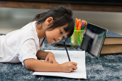 Girl holding mobile phone while sitting on table