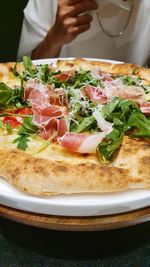 Delicious italian handmade pizza, prosciutto and arugula leaves, mozzarella cheese, closeup
