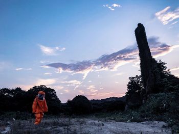 Person wearing protective clothing while walking on field against sky