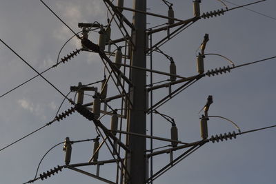 Low angle view of bird perching on electricity pylon against sky