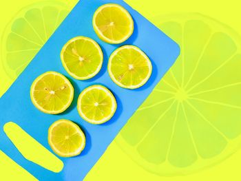 Zinging in at the last minute. refreshing lemon slices on bright blue and sunny yellow background