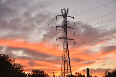 Low angle view of silhouette electricity pylon against sky during sunset