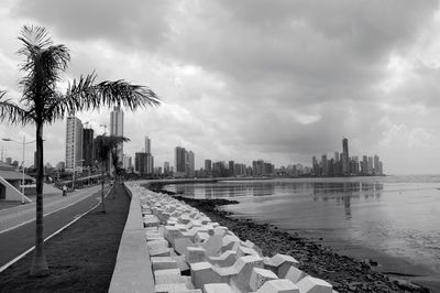 City at waterfront against cloudy sky