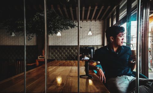 Young man sitting on table in restaurant