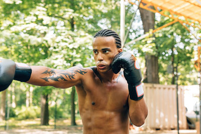 Shirtless man boxing on street