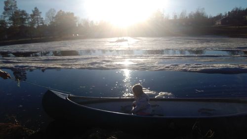 Boy standing in water at sunset