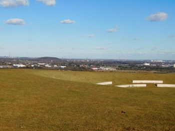 Scenic view of field by sea against sky