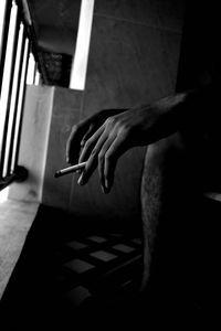 Close-up of hand holding cigarette at home