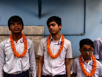 Portrait of friends standing against orange wall