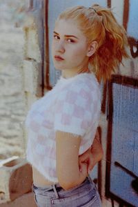 Portrait of young woman standing against wall