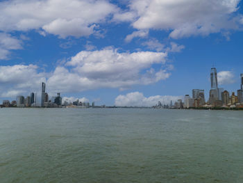 View of buildings by sea against cloudy sky