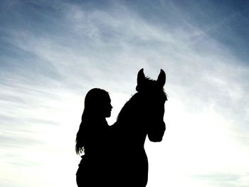 Low angle view of silhouette girl riding horse against sky