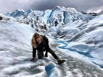 Full length portrait of woman hiking on snowcapped mountains during winter