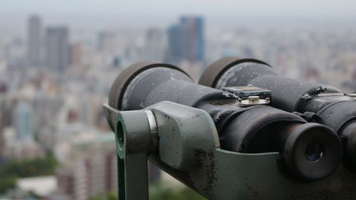 Close-up of machine part with city in background