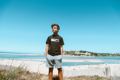 Full length of man standing on beach against clear sky