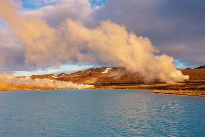 Drone footage through clouds blue lake by rugged terrain and mountains. iceland, northeast region