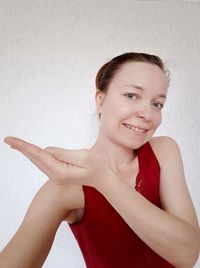 Portrait of smiling young woman against wall