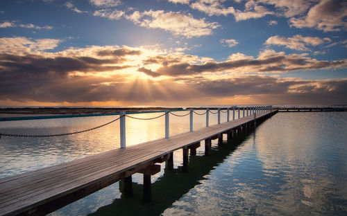 Pier over sea against sky during sunset