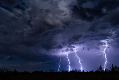 Low angle view of lightning over silhouette landscape at night