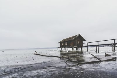 Lifeguard hut on beach against sky during winter