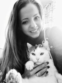 Portrait of young woman with cat sitting at home